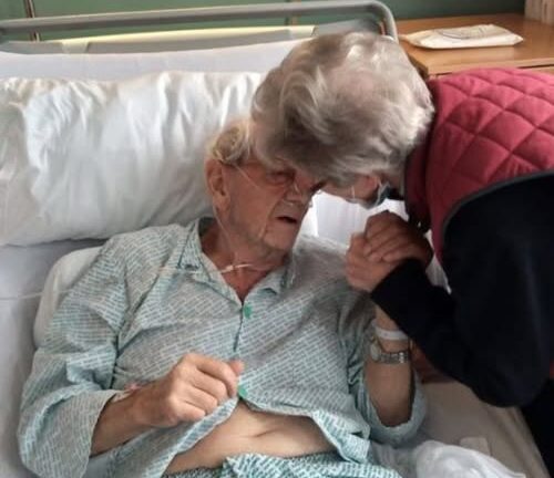 Two elderly individuals; one is a patient, the other is a visitor.
